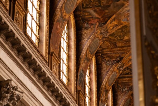 the ceiling of a building with columns and paintings on it