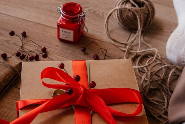 a wrapped present sitting on the floor next to a jar of jam